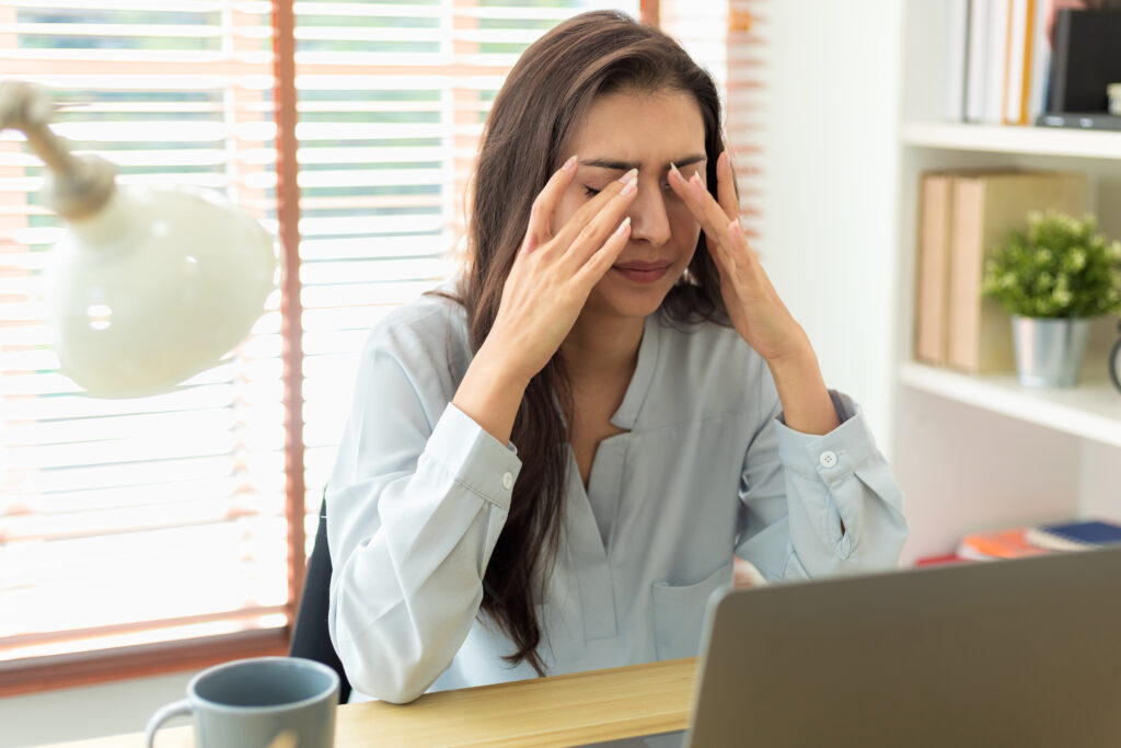 Femme avec une migraine devant un ordinateur