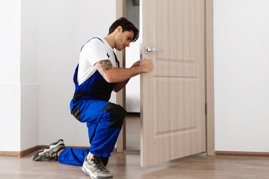 Ub homme installe une serrure connectée sur une porte d'entrée