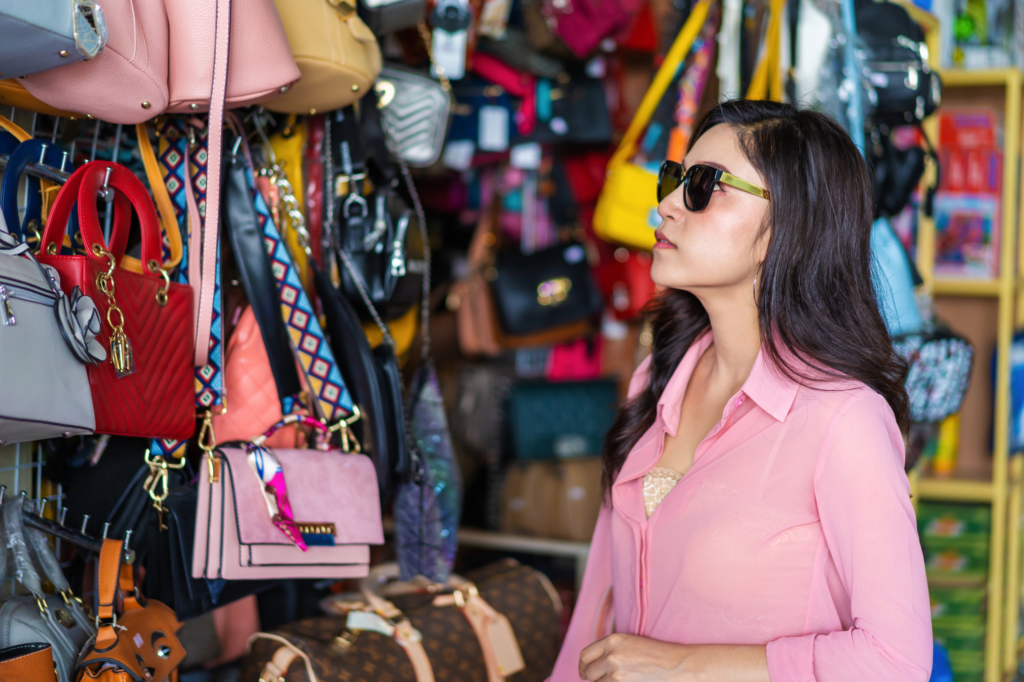 Femme debout devant une collection de sacs de toutes les couleurs et tailles, illustrant un constat de contrefaçon