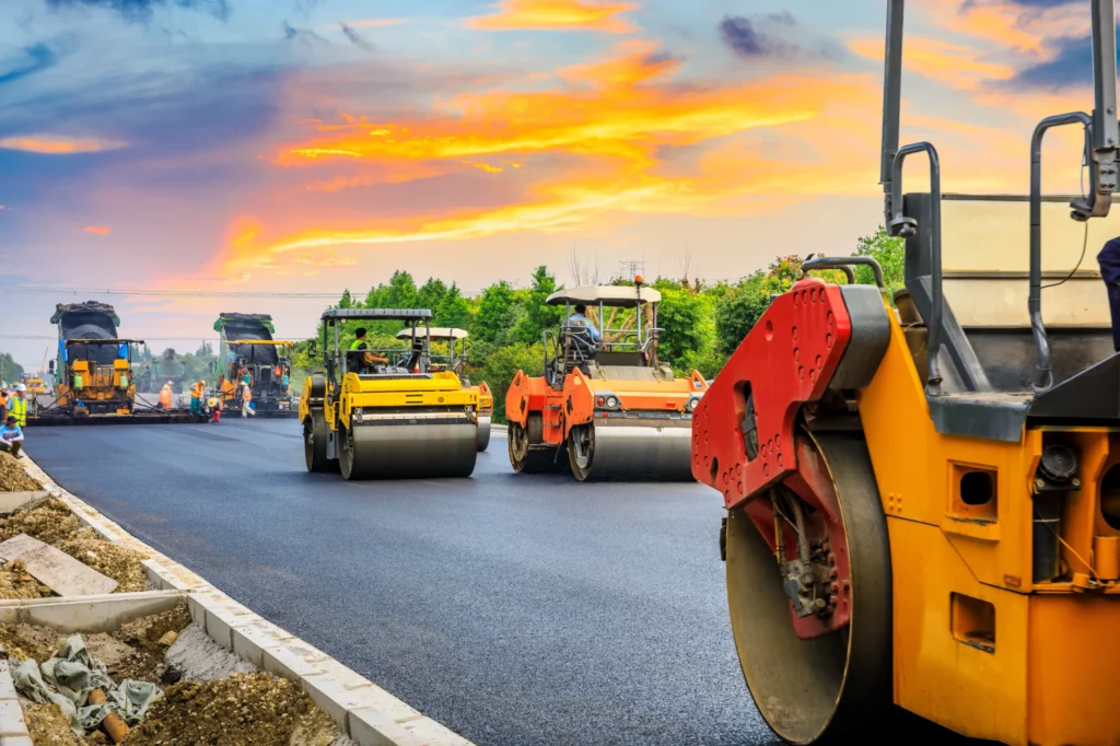 Chaussée récemment goudronnée avec des rouleaux compresseurs en train de circuler dessus, illustrant les travaux en cours pour le constat de voirie