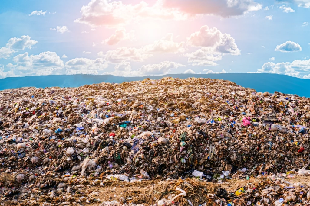 Détritus et déchets éparpillés dans une décharge sous un ciel clair, illustrant la nuisance visuelle causée par la pollution et la désorganisation des déchets