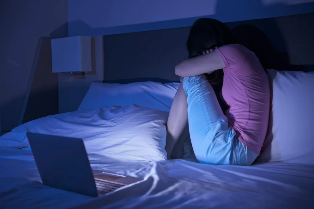 Jeune femme dépressive sur son lit, illustration de la détresse émotionnelle liée aux réseaux sociaux