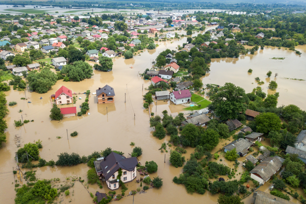 Vue aérienne montrant des habitations inondées, avec des zones d'eau submergeant les maisons, illustrant les dégâts causés par une catastrophe naturelle telle qu'une inondation