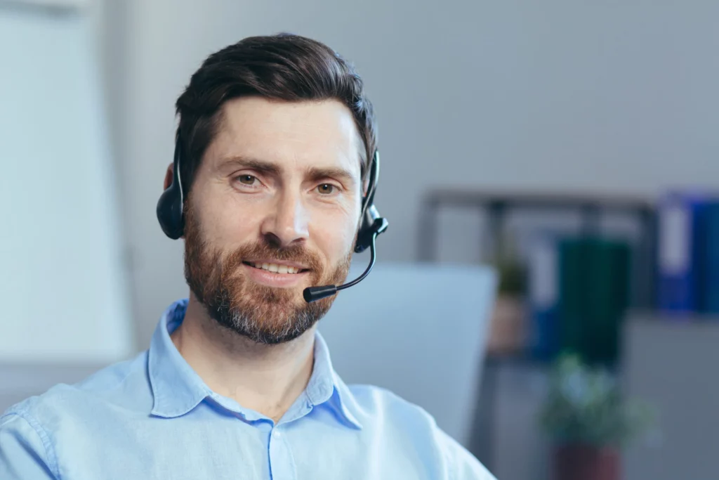 Informaticien avec un casque sur la tête regardant et souriant vers la caméra