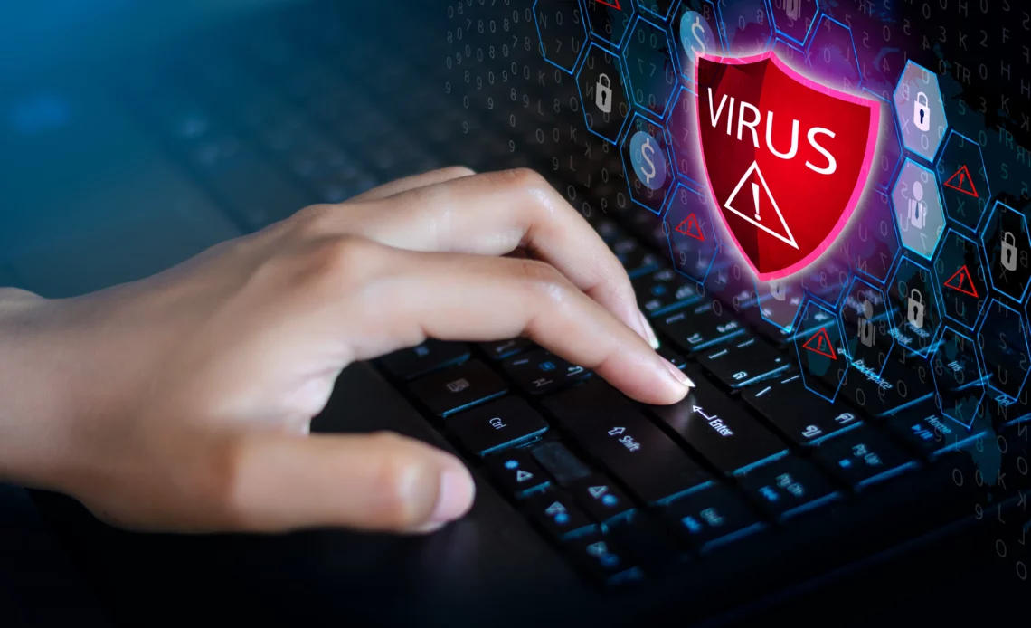Main tapant sur un clavier d'ordinateur infecté par un virus