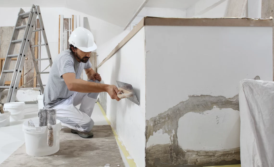 Bricoleur lissant un mur de plâtre pour illustrer le bruit de travaux le dimanche