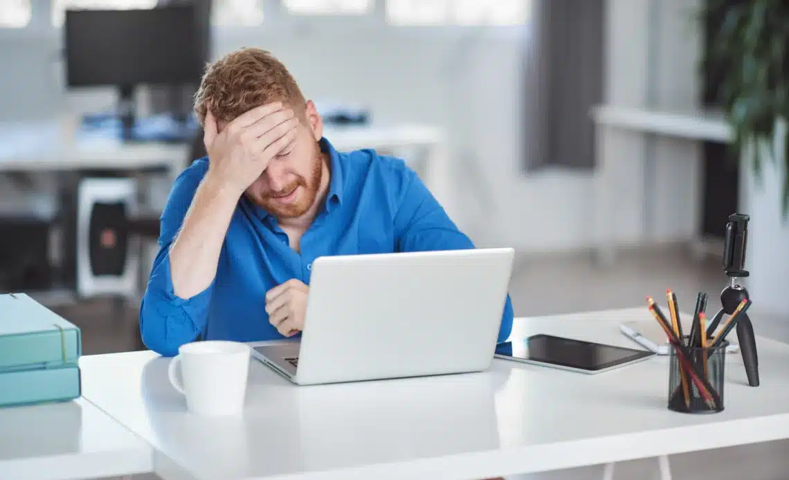 Un homme se prend la tête devant son ordinateur qui ne démarre pas