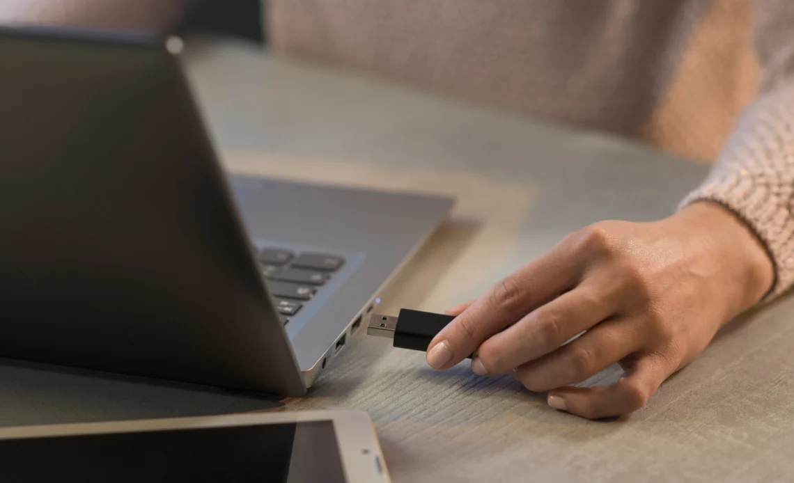 La main d'un homme est en train de connecter une clé USB d'installation Windows sur son ordinateur portable