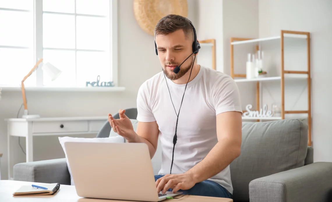 Un homme avec un casque sur les oreilles et devant un ordinateur pour illustrer l'utilisation de l'Assistance rapide Windows 11