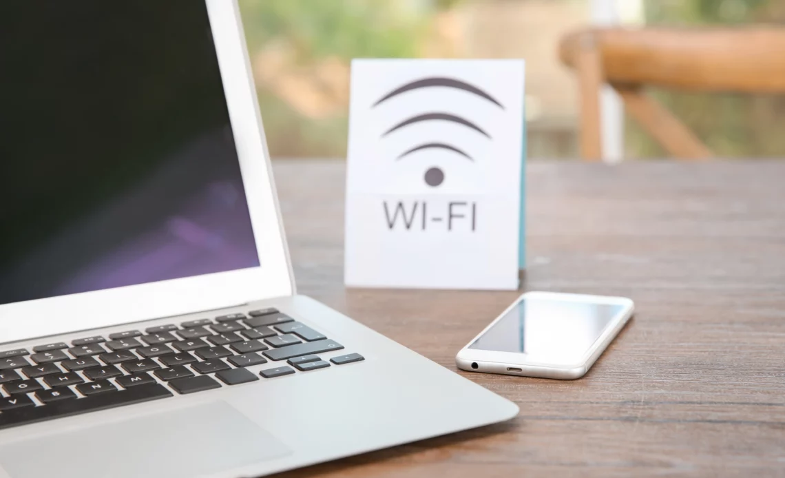 Un ordinateur et un téléphone portable posés sur une table à côté d'une borne wifi