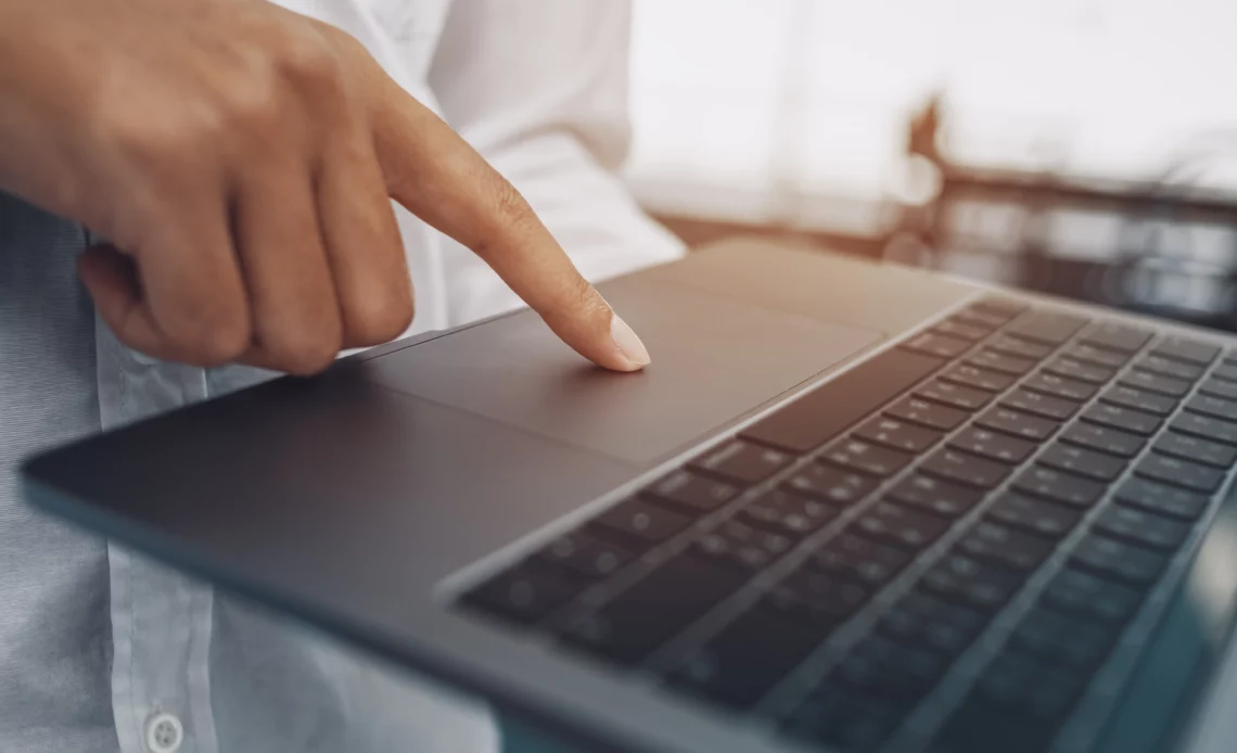 Un homme passe le doigt sur le trackpad d'un macBook